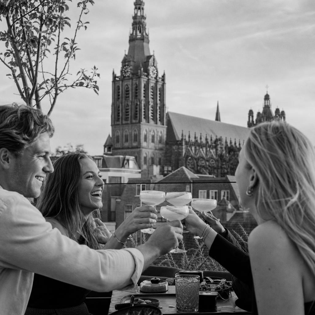 Terras in de Bossche binnenstad met cocktails en de toren van de Sint-Jan op de achtergrond